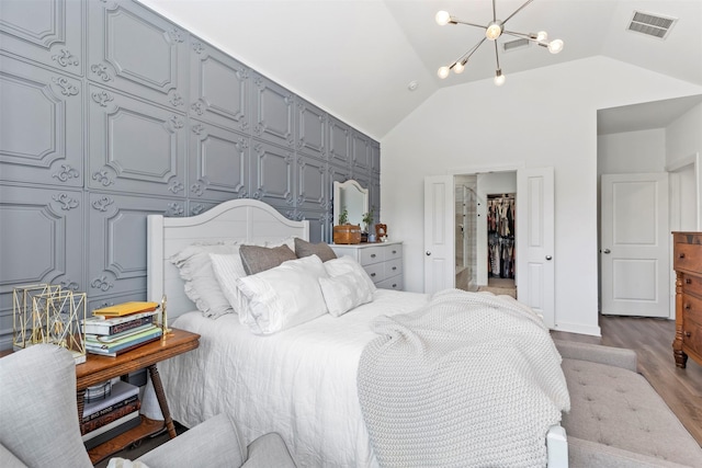 bedroom featuring hardwood / wood-style floors, lofted ceiling, and a notable chandelier