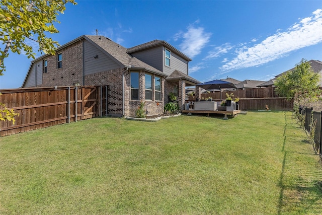 rear view of house featuring a lawn and a deck