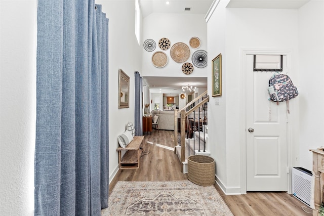 hall with a high ceiling and light hardwood / wood-style floors