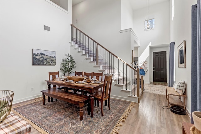 dining room with a high ceiling, a notable chandelier, and wood-type flooring