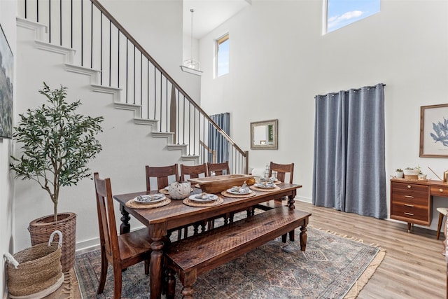 dining space with light hardwood / wood-style flooring and a high ceiling