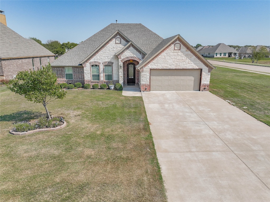 french country style house with a front lawn and a garage