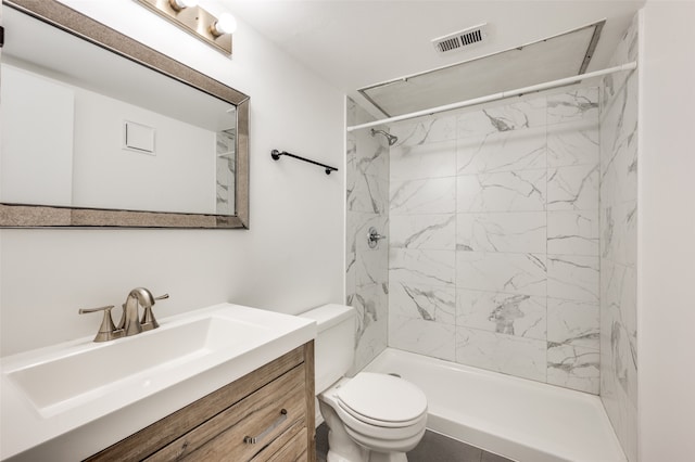 bathroom featuring vanity, toilet, and a tile shower