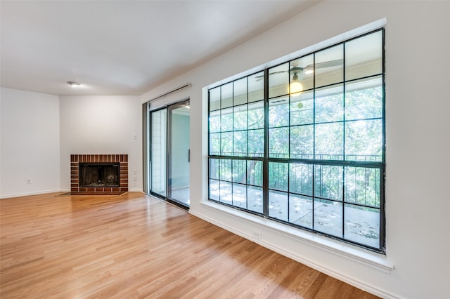 unfurnished living room featuring light hardwood / wood-style floors, a brick fireplace, and a healthy amount of sunlight