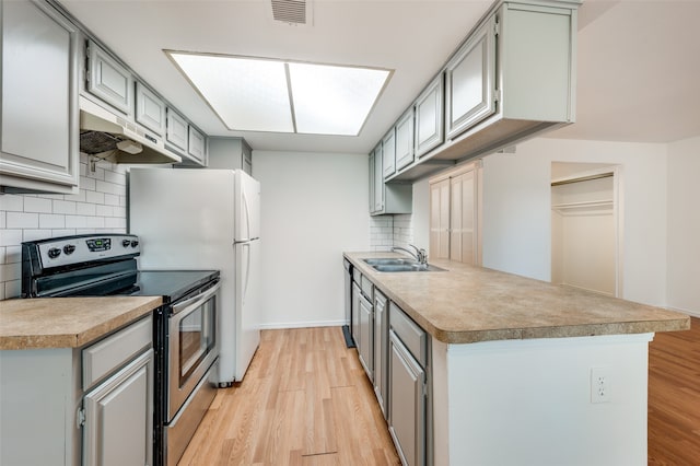 kitchen with decorative backsplash, light hardwood / wood-style flooring, sink, gray cabinets, and stainless steel appliances