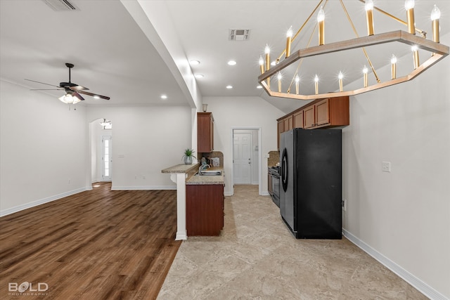 kitchen with black fridge, light hardwood / wood-style flooring, sink, vaulted ceiling, and ceiling fan