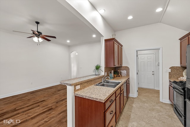 kitchen with lofted ceiling, decorative backsplash, black range with gas stovetop, kitchen peninsula, and sink