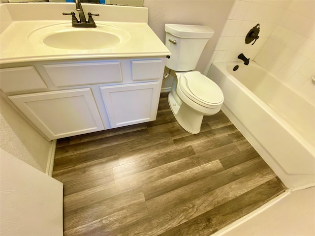 full bathroom with vanity, tiled shower / bath, hardwood / wood-style floors, and toilet