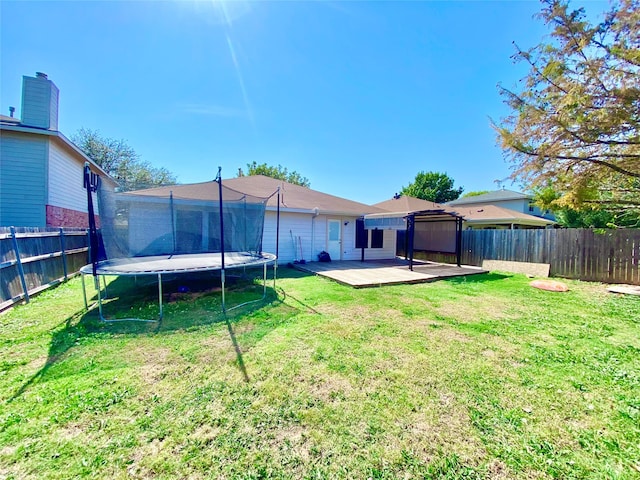 back of property with a yard, a trampoline, and a deck