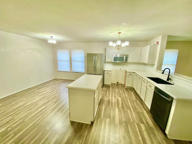 kitchen featuring sink, light wood-type flooring, a kitchen island, hanging light fixtures, and stainless steel appliances