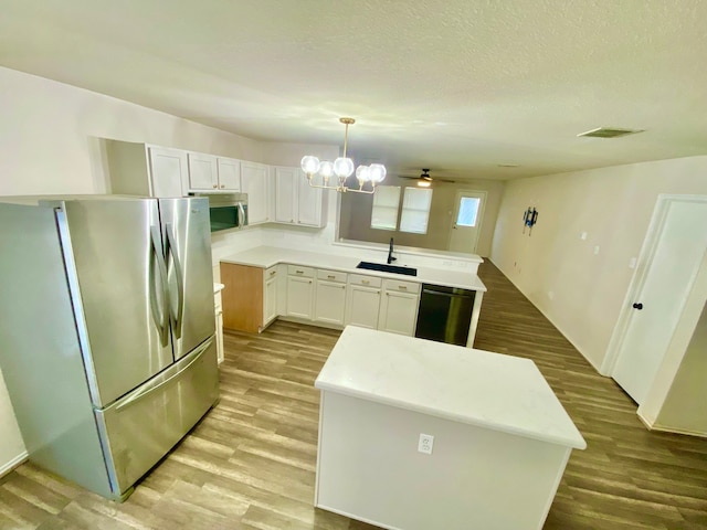 kitchen with white cabinetry, stainless steel appliances, sink, pendant lighting, and a center island