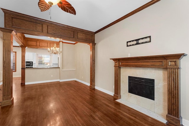 unfurnished living room featuring a tiled fireplace, dark wood-type flooring, ceiling fan with notable chandelier, and ornamental molding