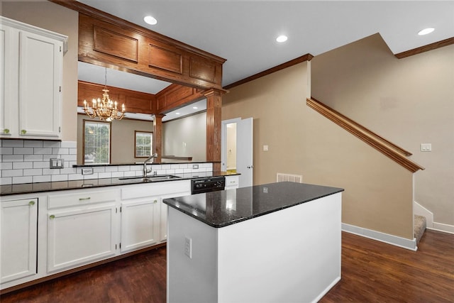 kitchen featuring white cabinets, a kitchen island, dark stone counters, and sink