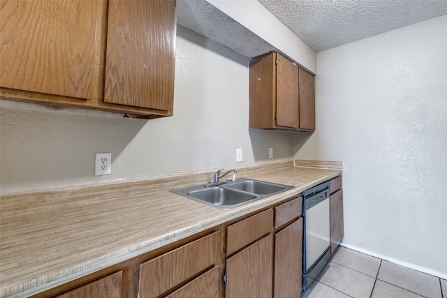 kitchen with sink, light tile patterned floors, a textured ceiling, and dishwasher