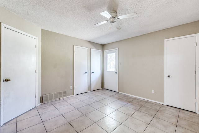 unfurnished bedroom featuring a textured ceiling, light tile patterned floors, and ceiling fan