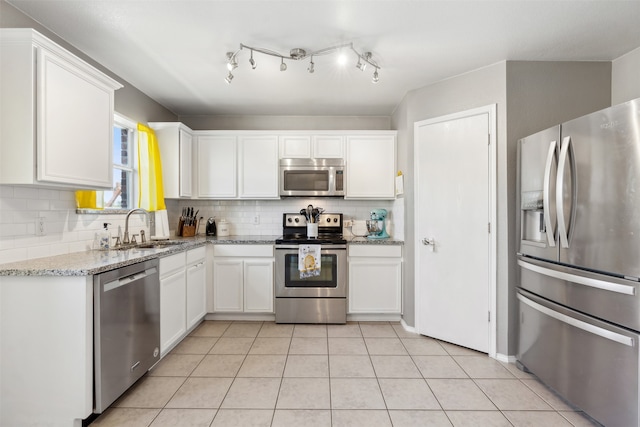 kitchen with sink, light stone counters, backsplash, white cabinets, and appliances with stainless steel finishes