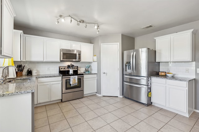 kitchen with white cabinetry, sink, light stone counters, light tile patterned flooring, and appliances with stainless steel finishes