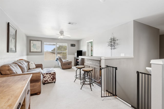 living room with bar area, light carpet, and ceiling fan