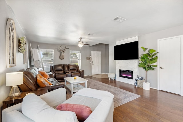 living room with a stone fireplace, ceiling fan, and dark hardwood / wood-style flooring