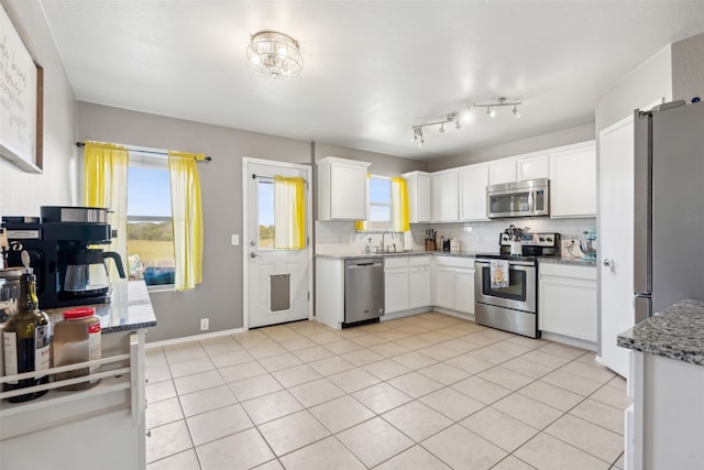 kitchen with white cabinetry, sink, light tile patterned flooring, and stainless steel appliances