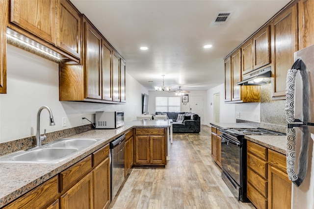 kitchen with kitchen peninsula, sink, an inviting chandelier, appliances with stainless steel finishes, and light hardwood / wood-style floors