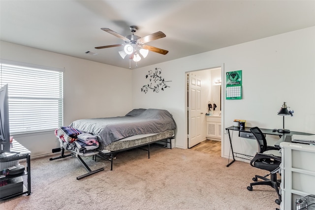 bedroom featuring ensuite bath, light colored carpet, and ceiling fan