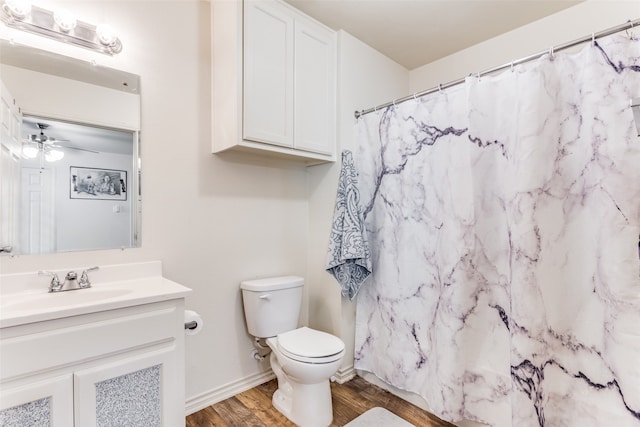 bathroom with hardwood / wood-style floors, ceiling fan, toilet, vanity, and curtained shower