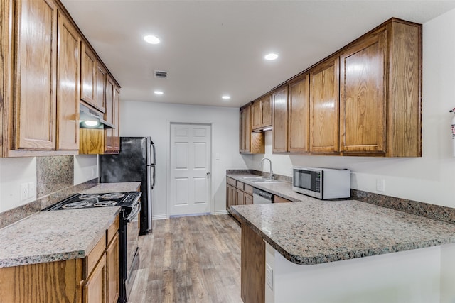 kitchen with light hardwood / wood-style flooring, kitchen peninsula, black appliances, and light stone counters