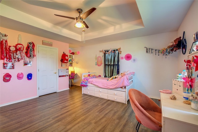 bedroom with a raised ceiling, ceiling fan, and dark hardwood / wood-style floors