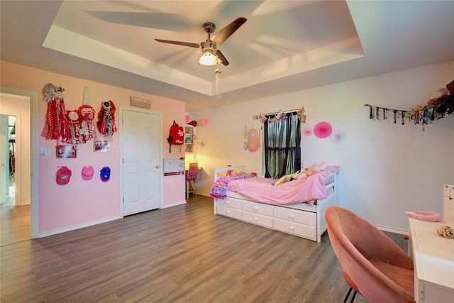 bedroom with ceiling fan, dark hardwood / wood-style flooring, and a raised ceiling