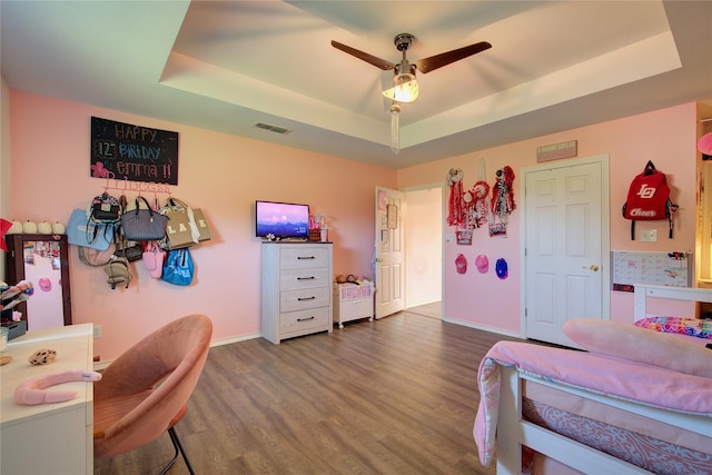 bedroom featuring a tray ceiling, ceiling fan, and wood-type flooring