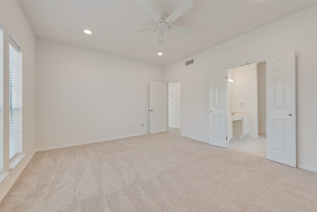 unfurnished bedroom featuring connected bathroom, light carpet, and ceiling fan