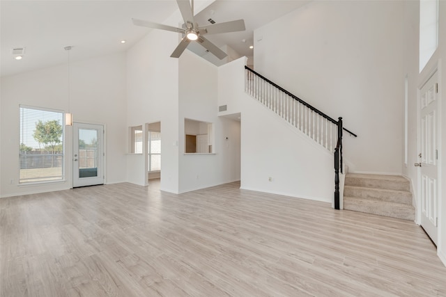 unfurnished living room with light wood-type flooring, high vaulted ceiling, and plenty of natural light