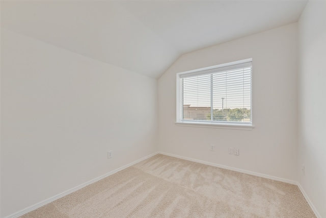 spare room featuring light carpet and lofted ceiling