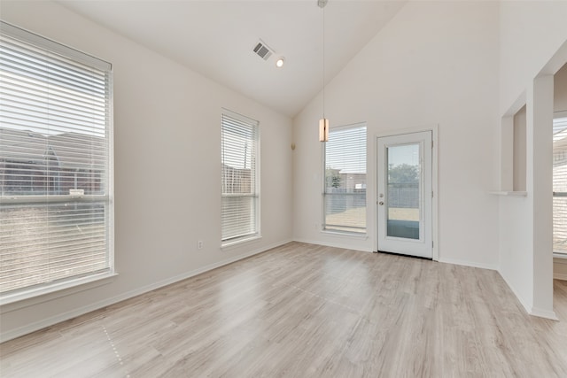 spare room featuring high vaulted ceiling, a healthy amount of sunlight, and light hardwood / wood-style flooring