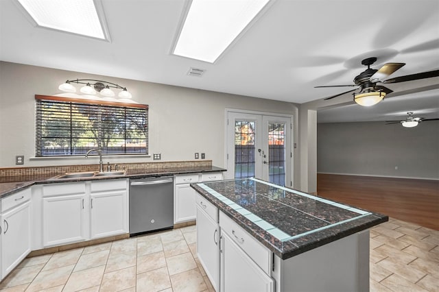 kitchen featuring sink, dishwasher, a center island, plenty of natural light, and white cabinets