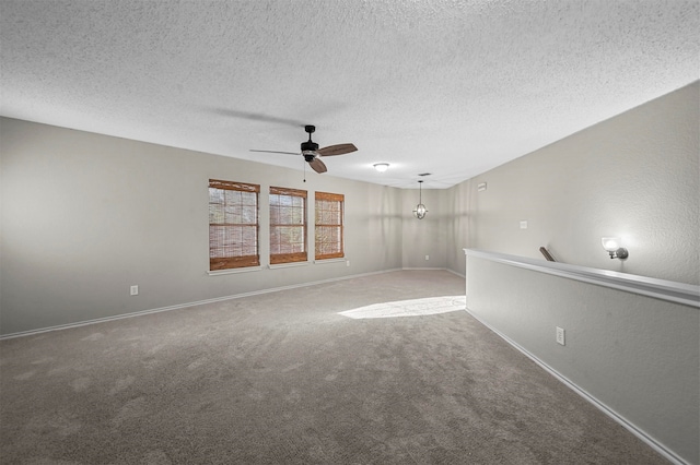 unfurnished room featuring carpet floors, a textured ceiling, and ceiling fan with notable chandelier