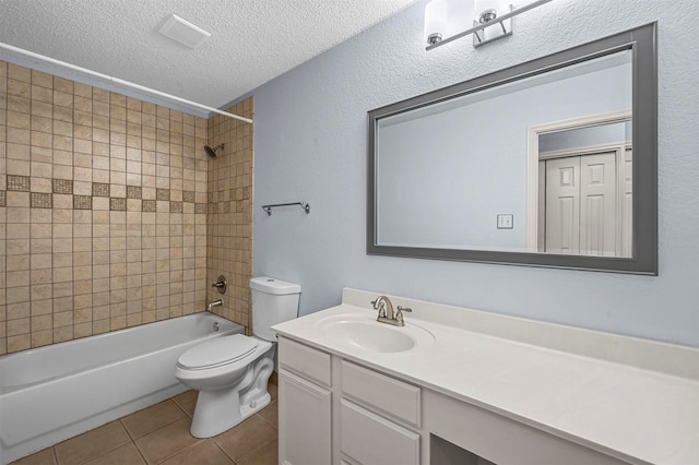 full bathroom featuring a textured ceiling, toilet, tile patterned floors, tiled shower / bath, and vanity