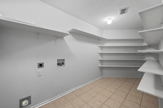 laundry room featuring hookup for an electric dryer, hookup for a washing machine, a textured ceiling, and light tile patterned flooring