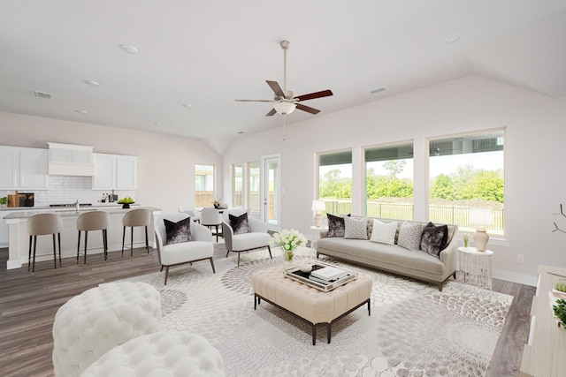 living room featuring light hardwood / wood-style floors, vaulted ceiling, and ceiling fan