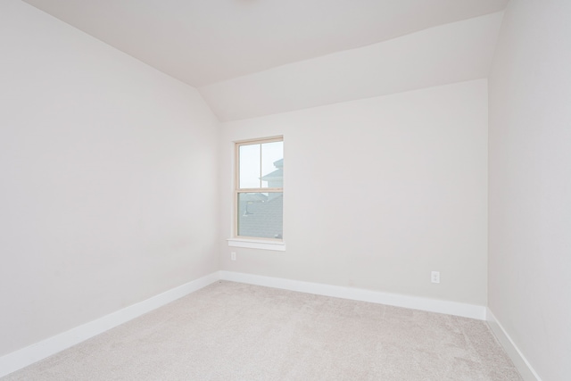 unfurnished room featuring vaulted ceiling and carpet flooring