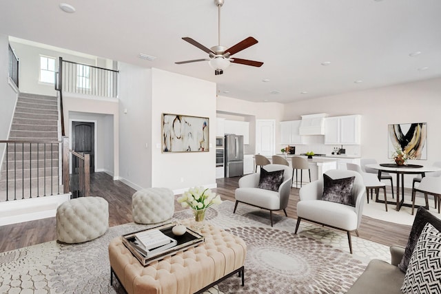 living room with a high ceiling, hardwood / wood-style flooring, and ceiling fan