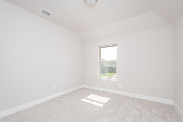 carpeted spare room with vaulted ceiling