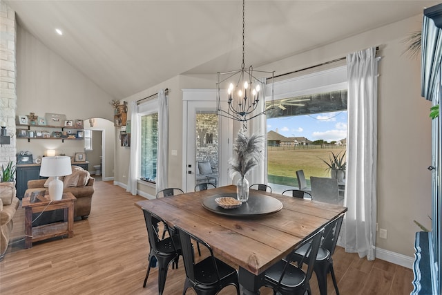 dining room with a notable chandelier, light hardwood / wood-style floors, a healthy amount of sunlight, and vaulted ceiling