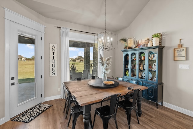 dining area featuring lofted ceiling, wood-type flooring, and an inviting chandelier