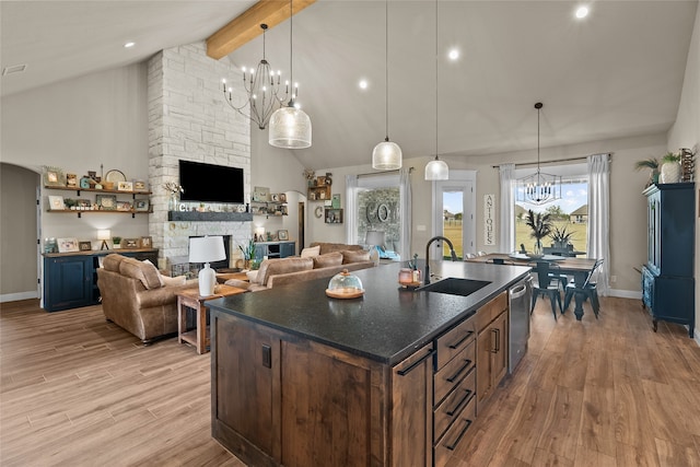 kitchen with sink, dishwasher, a stone fireplace, light hardwood / wood-style floors, and beamed ceiling