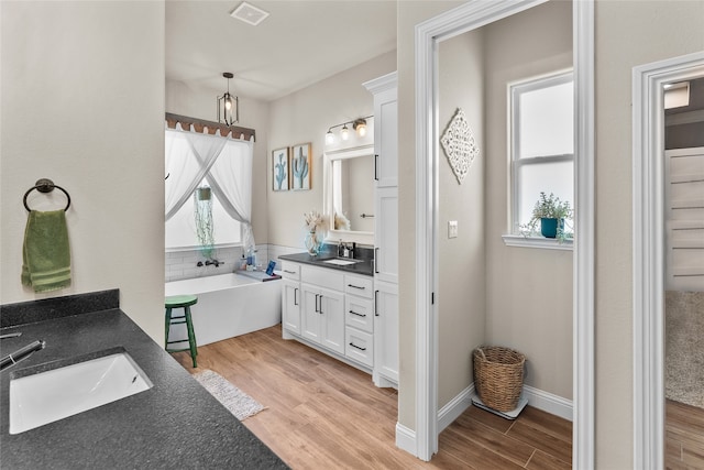 bathroom featuring vanity, hardwood / wood-style flooring, and a bath