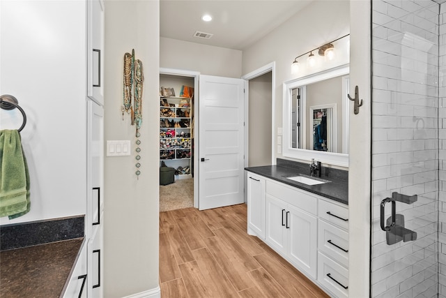 bathroom with vanity, tiled shower, and hardwood / wood-style floors