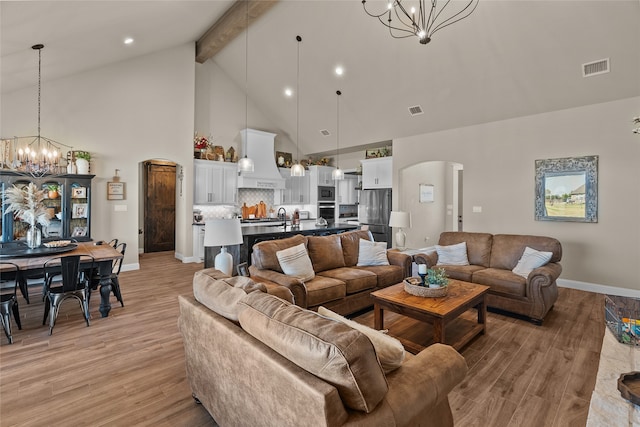 living room with light hardwood / wood-style floors, beam ceiling, sink, a notable chandelier, and high vaulted ceiling