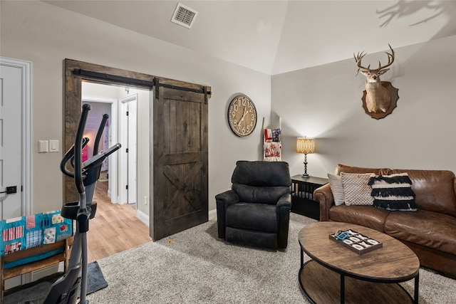 living room featuring hardwood / wood-style flooring, vaulted ceiling, and a barn door